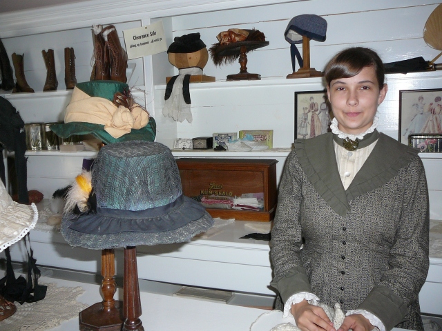 Acting as a customer in a store, in this case at the milliner's, is a common example of visitors engaged in second person interpretation. 1885 Street, Fort Edmonton Park, summer 2012. Photograph by Lauren Markewicz.